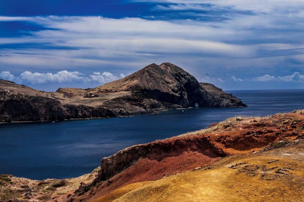 A rugged coastline with a prominent mountain and a deep blue sea.
