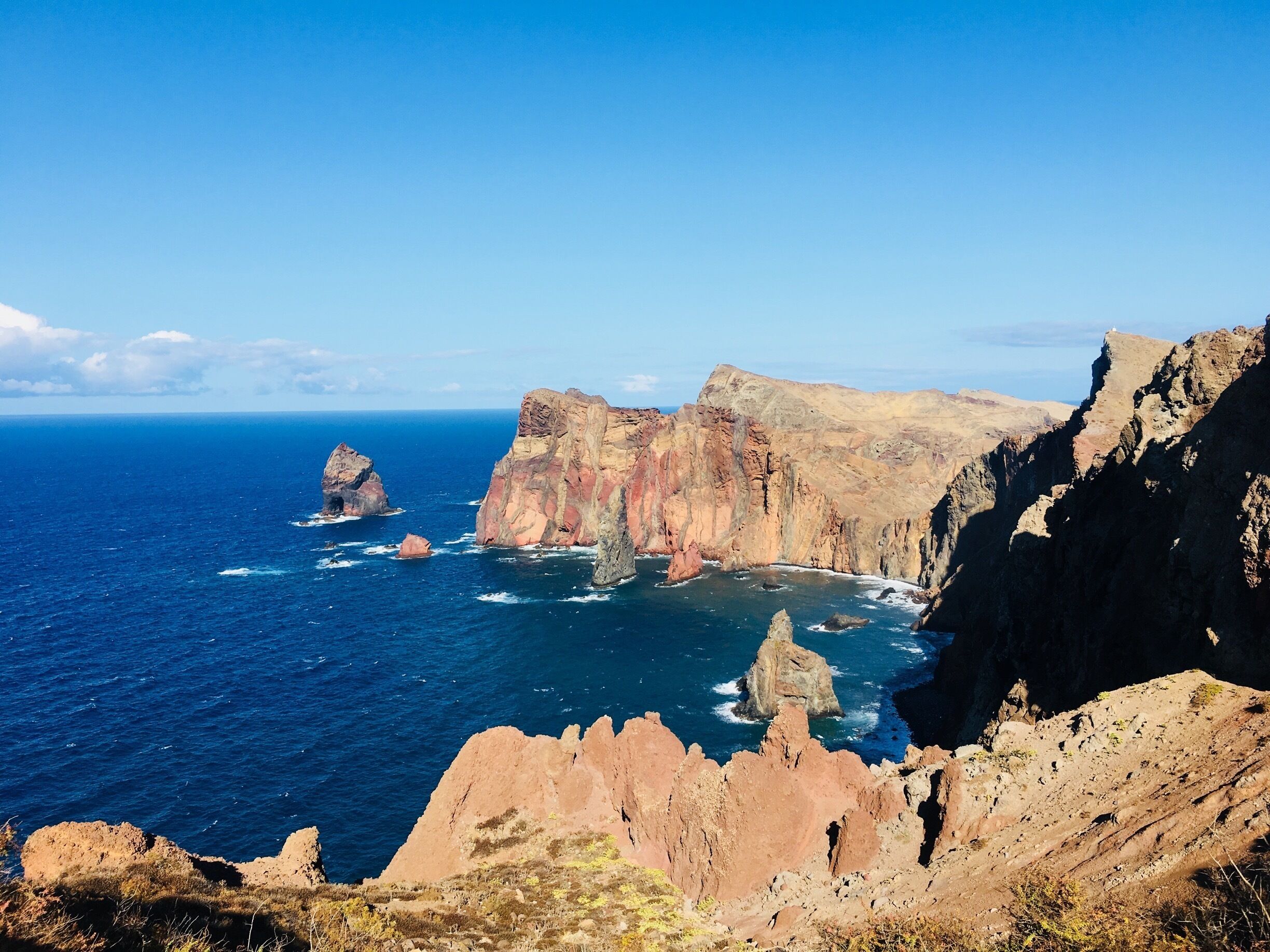 A coastal landscape with rugged cliffs and a clear blue sea.