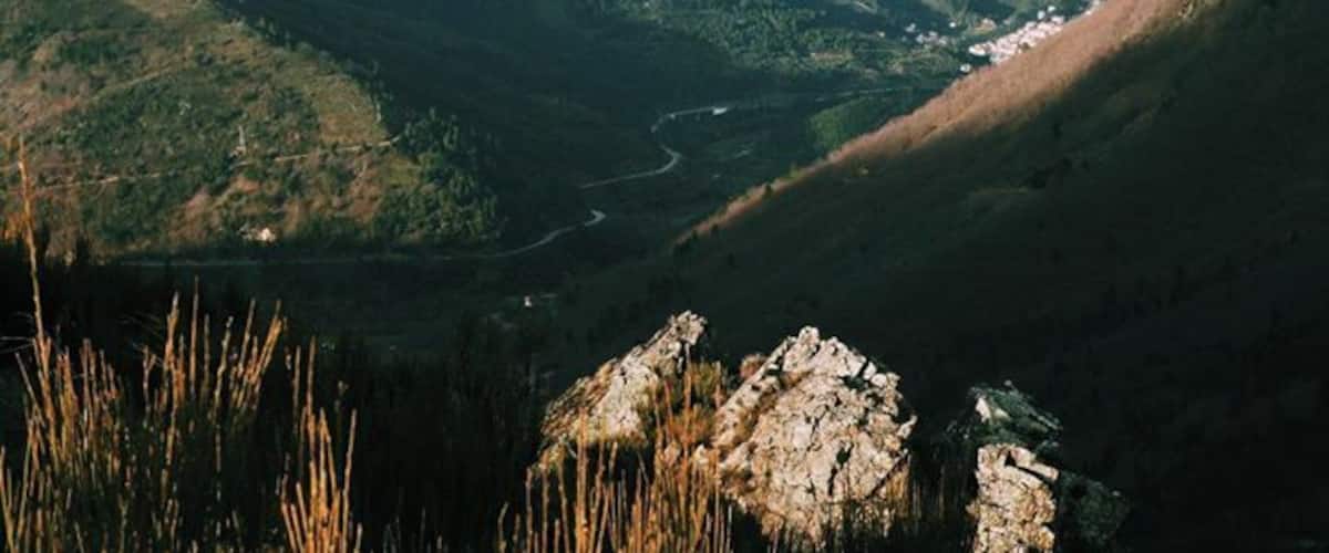 A valley with a river, surrounded by mountains and rocky outcrops.