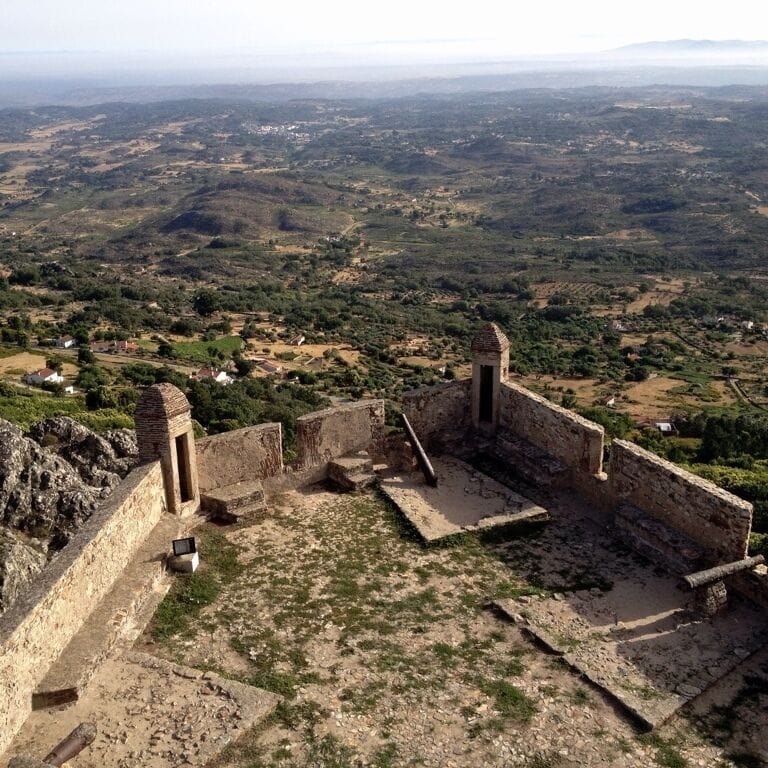 An ancient stone fortress with a panoramic view of a hilly landscape.