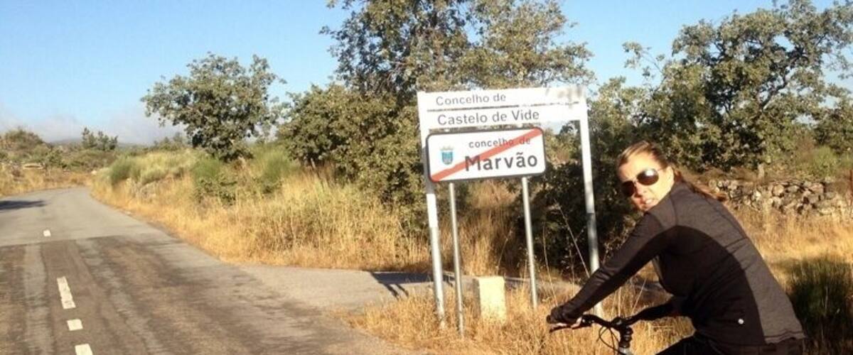 A cyclist on a road with a sign indicating Marvão.
