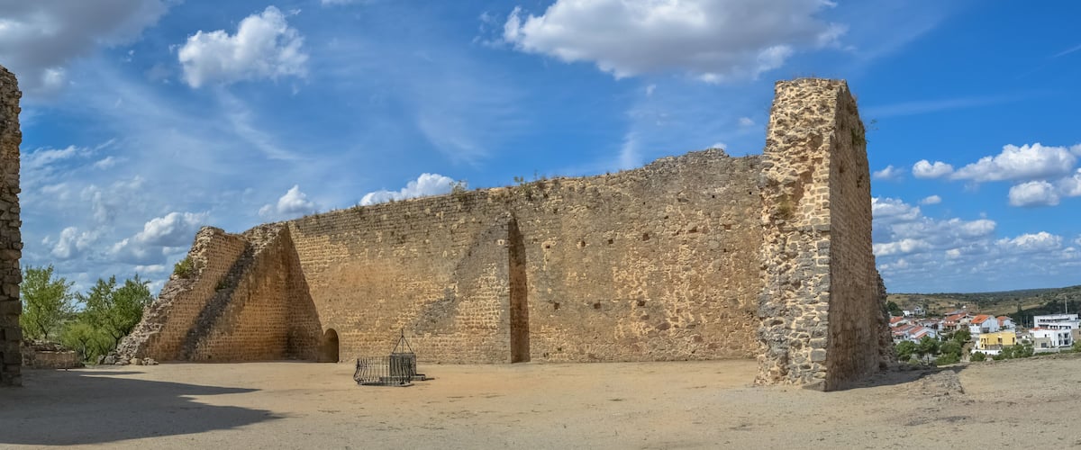 Ancient stone ruins with a clear sky and distant buildings.