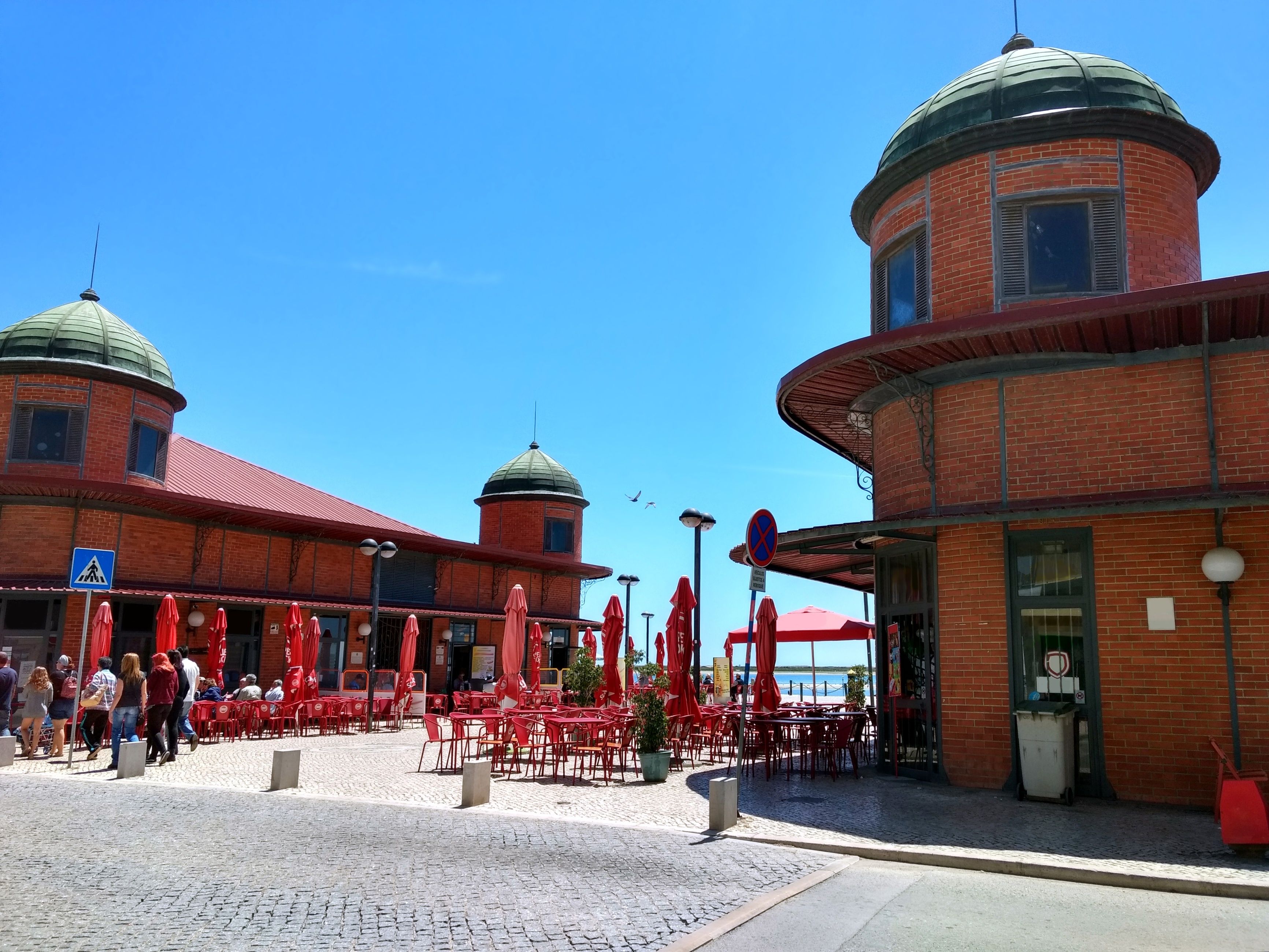 A courtyard with red tables and chairs, a pedestrian crossing sign, and a water tower.