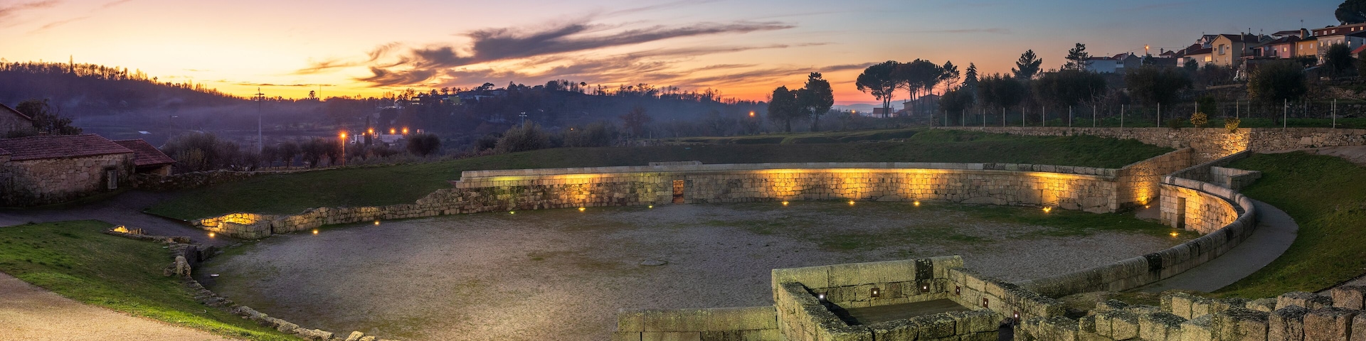 A historical fortification at sunset with surrounding buildings and a clear sky.
