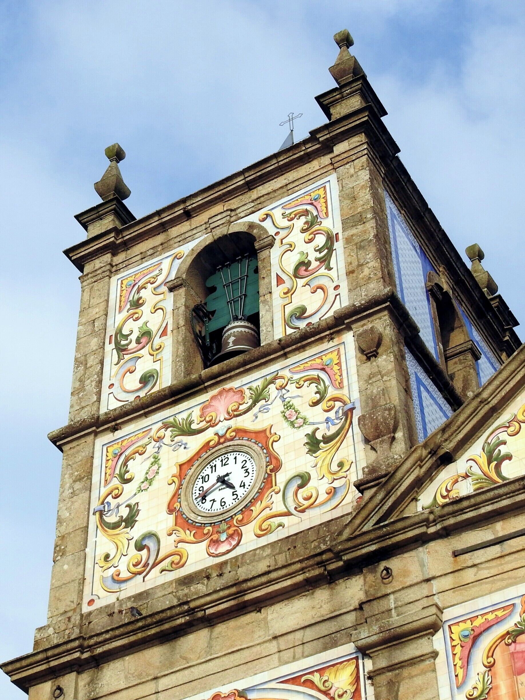A clock tower with ornate decorations and a bell.