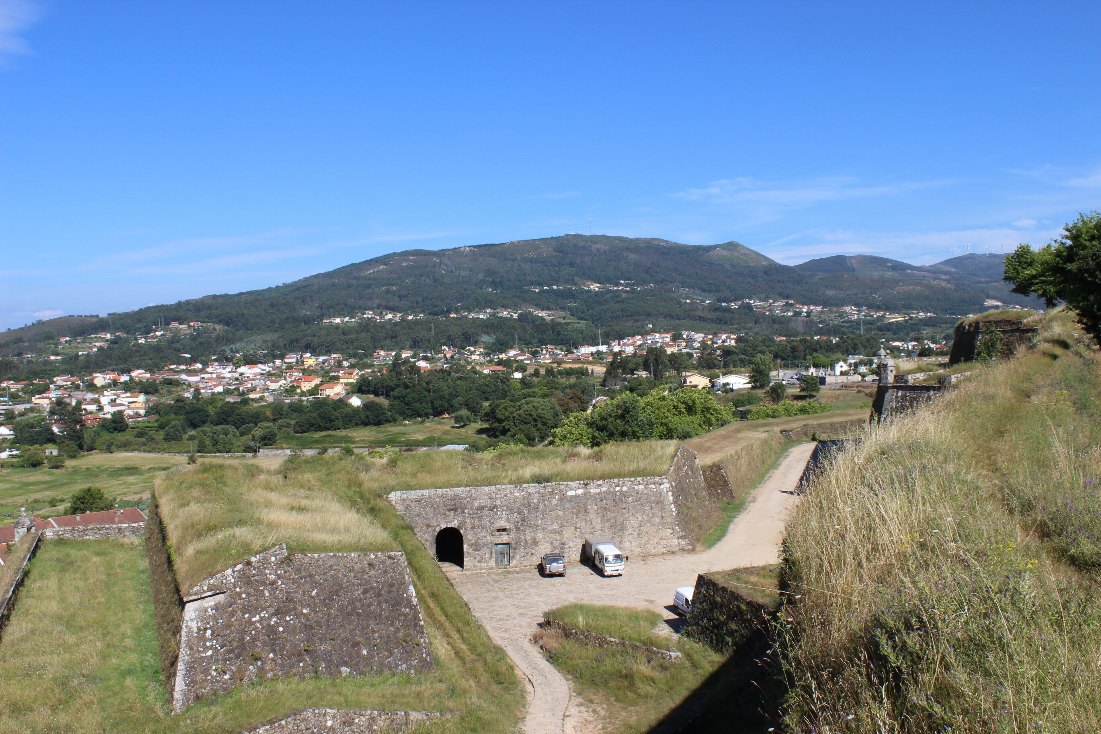 A historical fortification with a clear view of a town and mountains in the background.