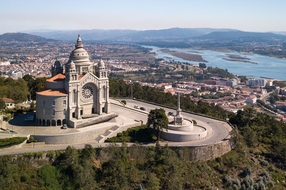 A historic cathedral with a prominent dome and bell tower, surrounded by a fortified wall and overlooking a river and cityscape.