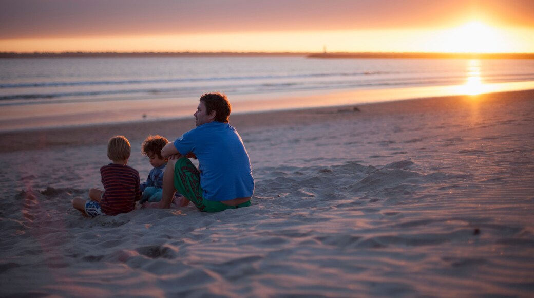Father with two kids sitting on beach during sunset, Viana do Castelo, Norte Region, Portugal