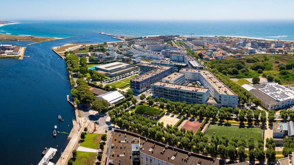 An aerial view of a coastal city with a river, industrial buildings, and residential areas.