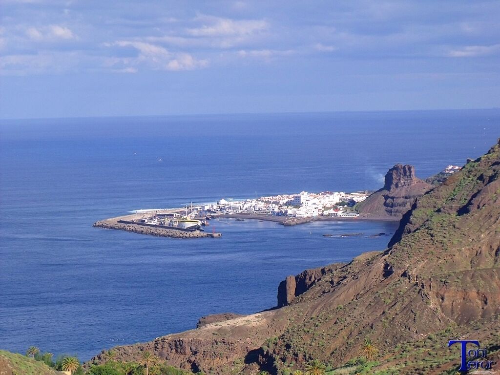 A coastal town with a rocky cliff and a small island with buildings.