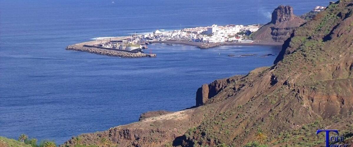 A coastal town with a rocky cliff and a small island with buildings.