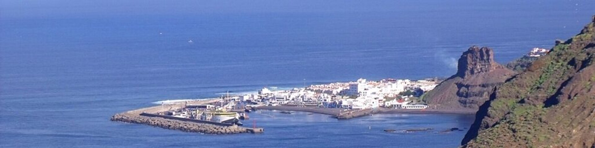 A coastal town with a rocky cliff and a small island with buildings.