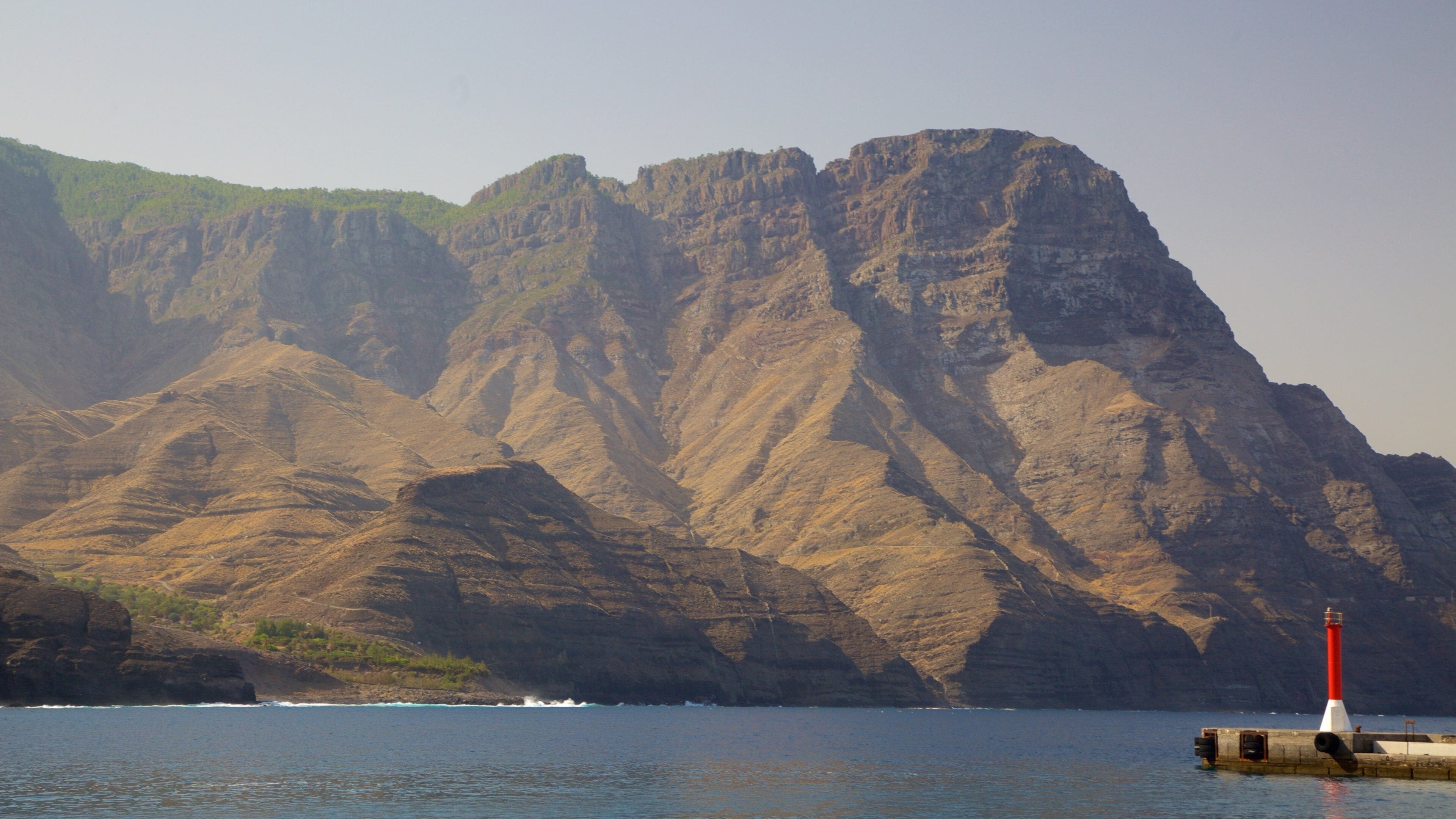 Agaete que incluye un faro, montañas y costa escarpada