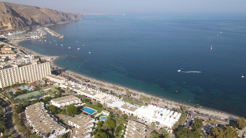 A coastal resort area with a beach, swimming pools, and a marina.