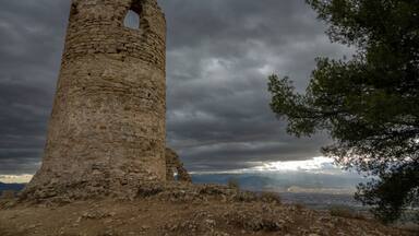 View of the medieval tower of Albolote (Spain) next to a tree on a stormy day