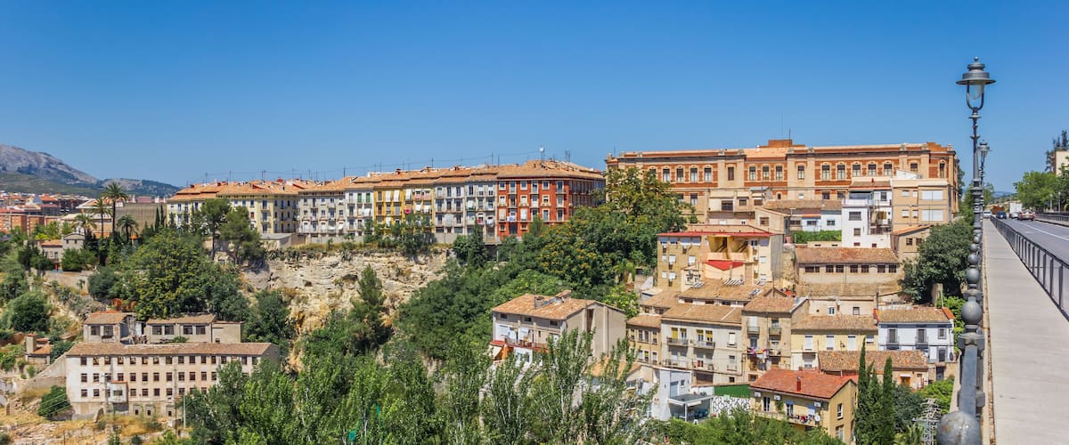 A hillside town with colorful buildings, a bridge, and a mountain in the background.