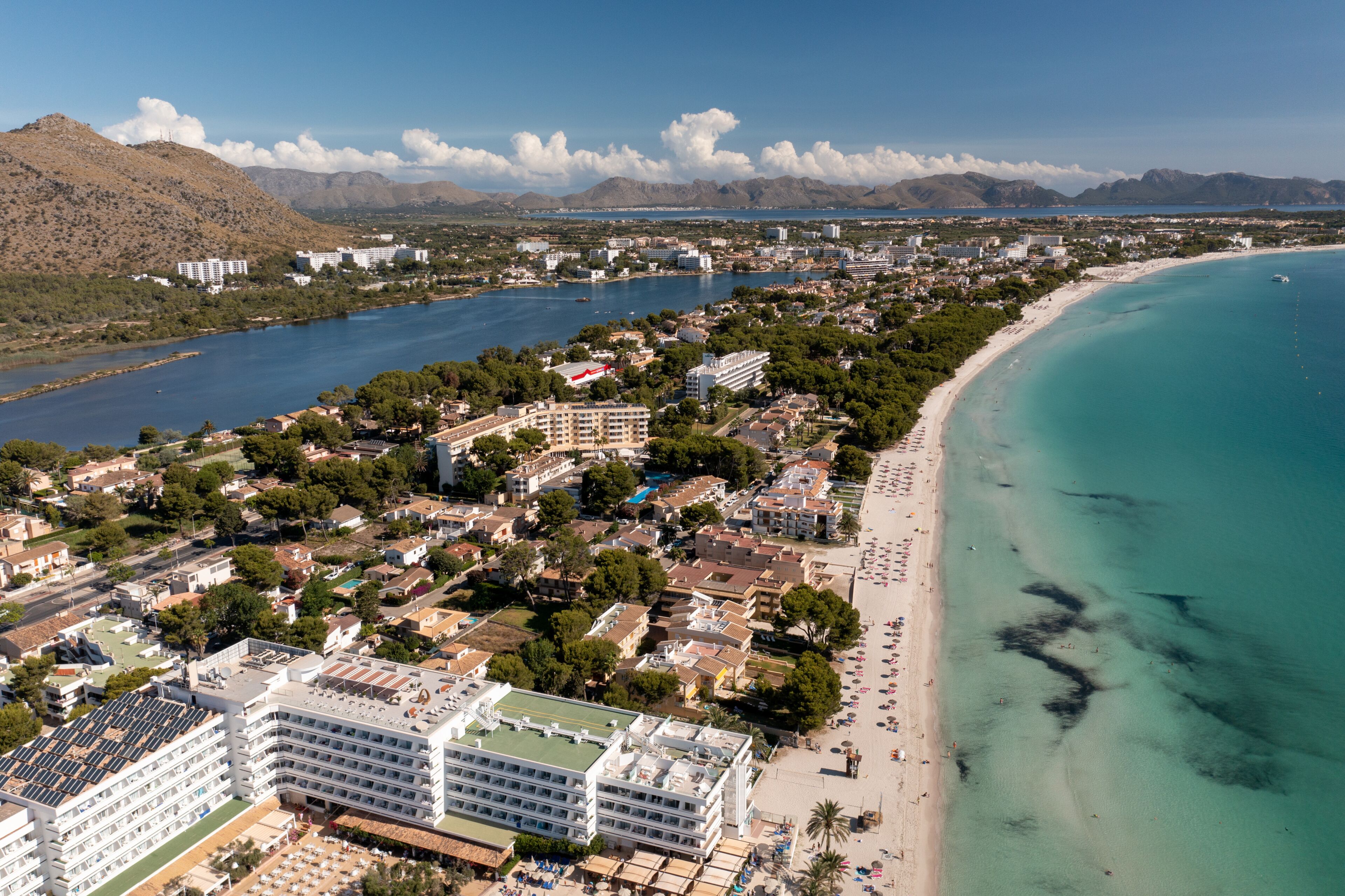 A coastal city with a beach, a river, and mountains in the background.