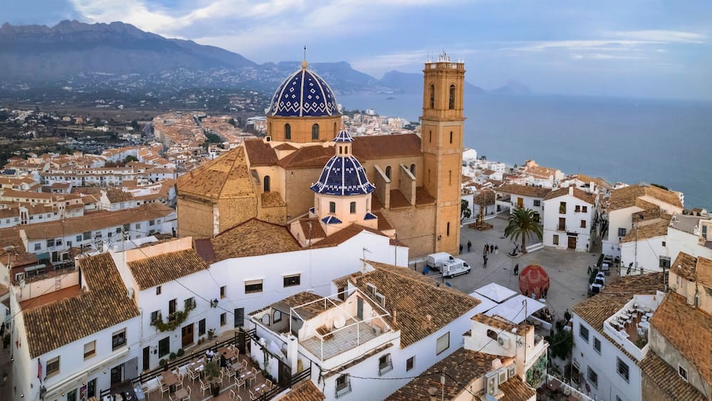 Une ville côtière qui se distingue par une église remarquable, avec ses coupoles bleues et son clocher.