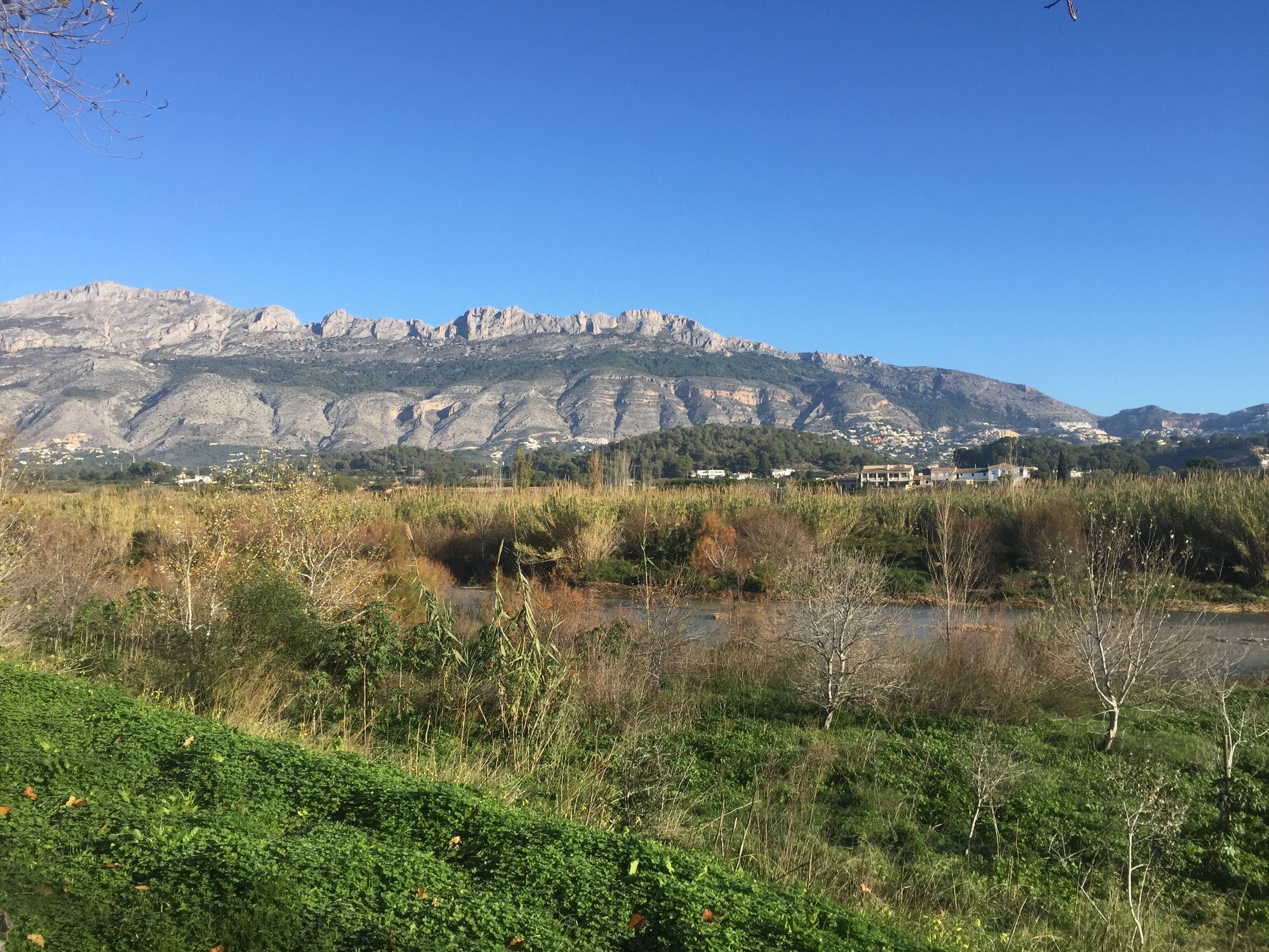 A mountainous landscape with a river in the foreground and a town in the background.