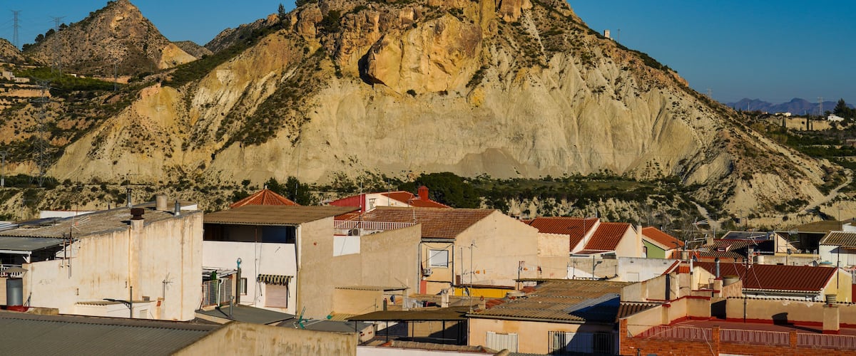 A mountainous landscape with a prominent peak and a town in the foreground.