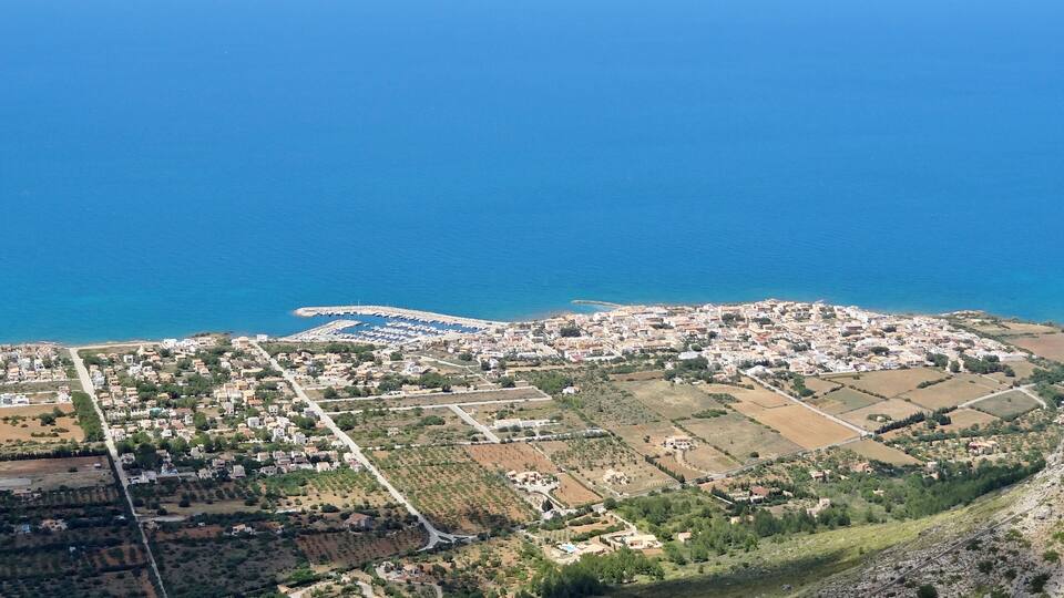 A coastal town with a marina, residential areas, and agricultural fields.