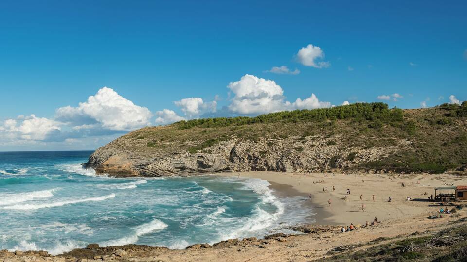 A coastal beach with rocky cliffs and a sandy shore.