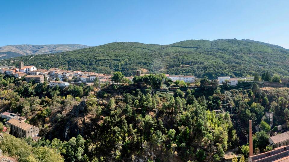 A hillside village with buildings, a bridge, and a mountain in the background.