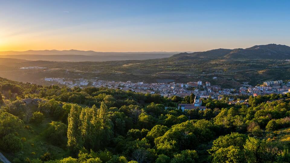 A city nestled in a valley with mountains in the background and a clear sky.