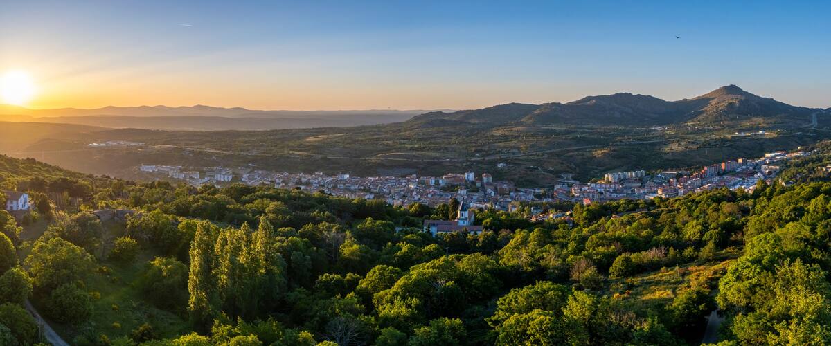 A city nestled in a valley with mountains in the background and a clear sky.