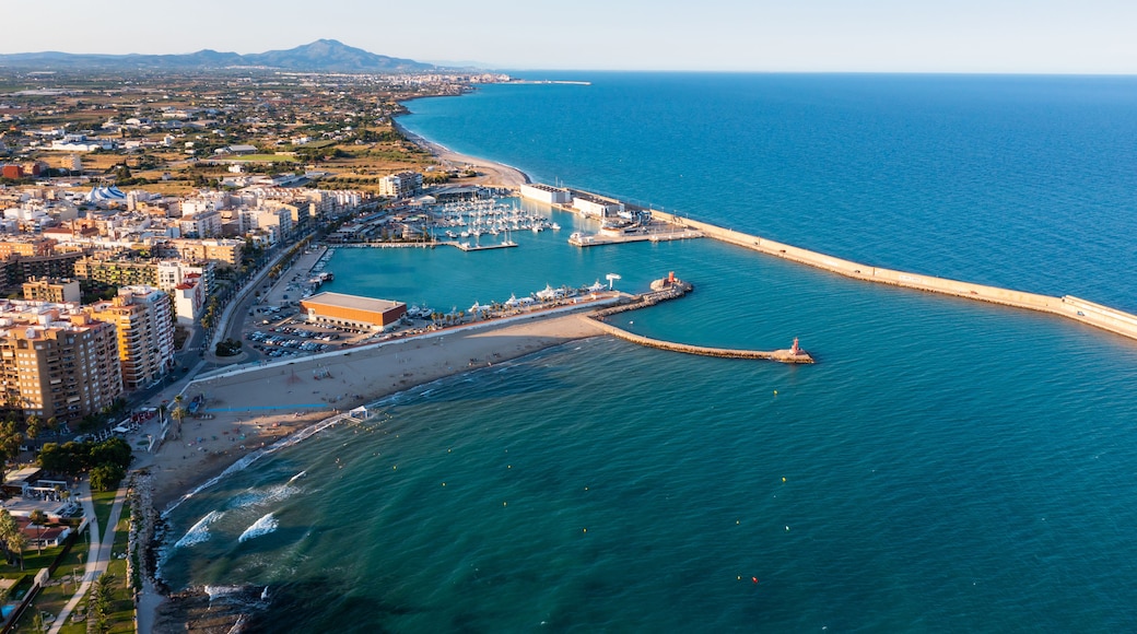 Uma cidade costeira com um porto, praia e um cais extenso que se projeta para o mar.