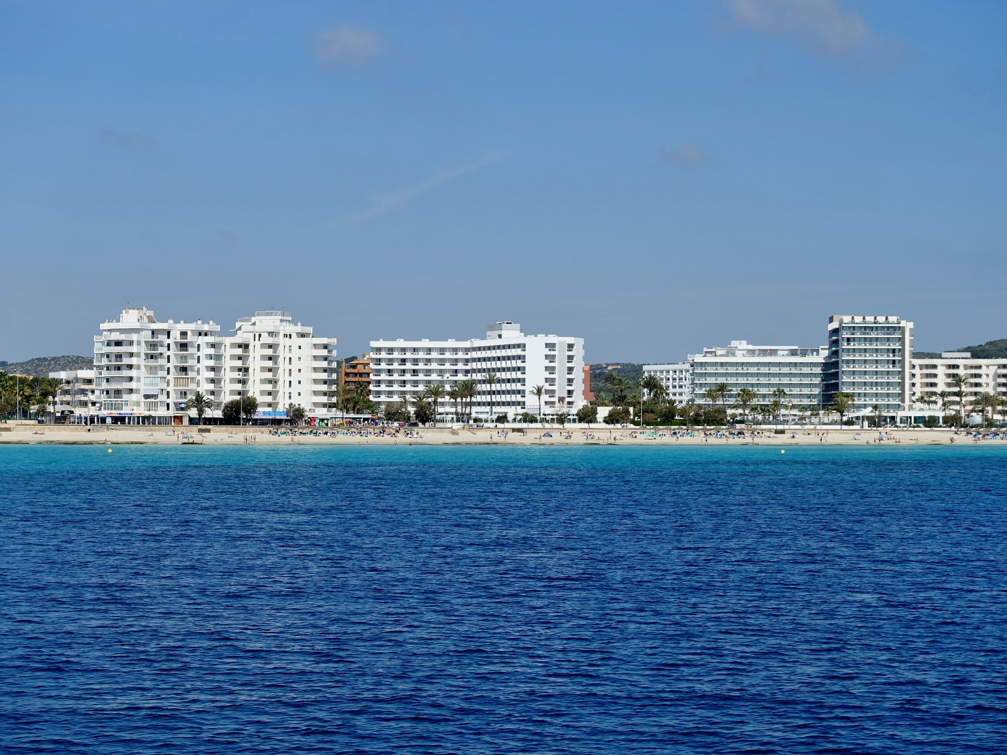 A coastal city with a beach and several white multi-story buildings.