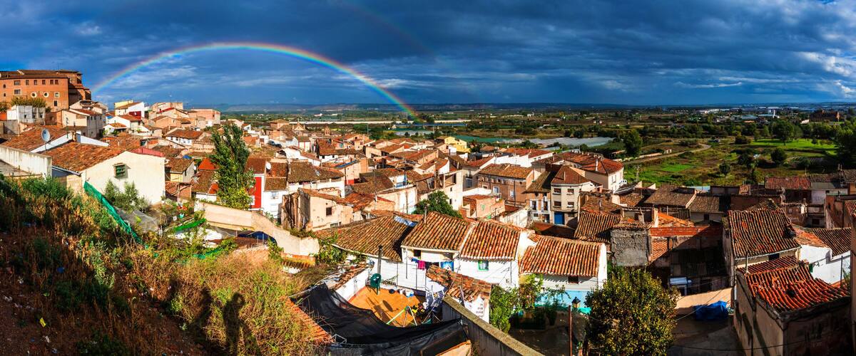 A town with a prominent church, a river, and a rainbow.