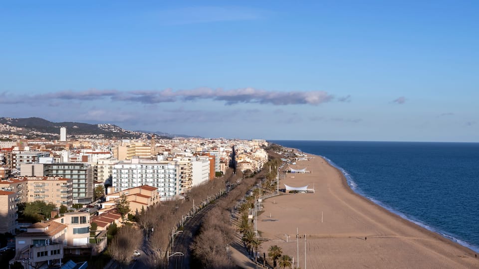 A coastal cityscape with a beach, buildings, and a clear sky.