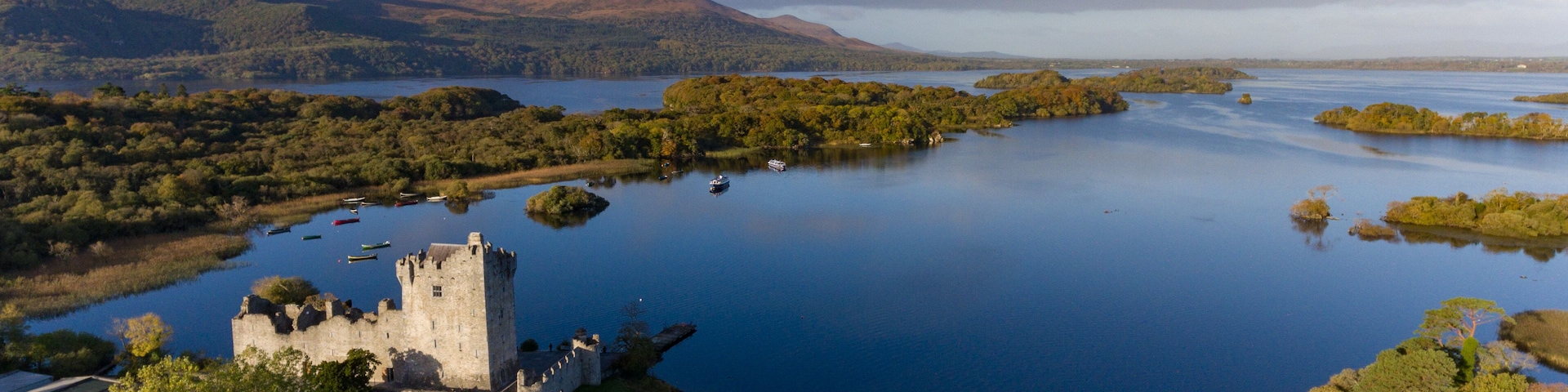 A castle by a lake surrounded by mountains.