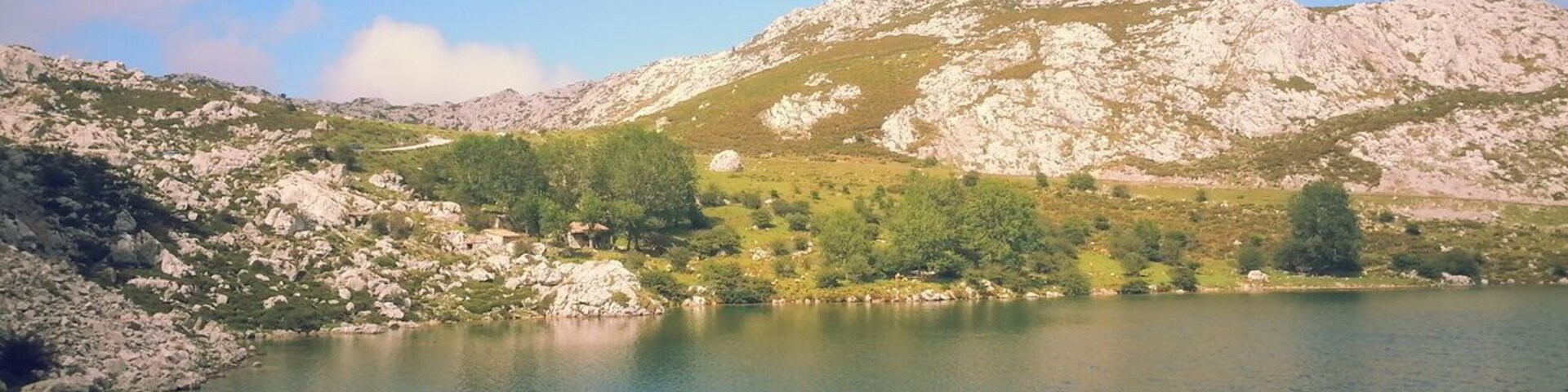 Un lago rodeado de montañas rocosas y vegetación escasa.