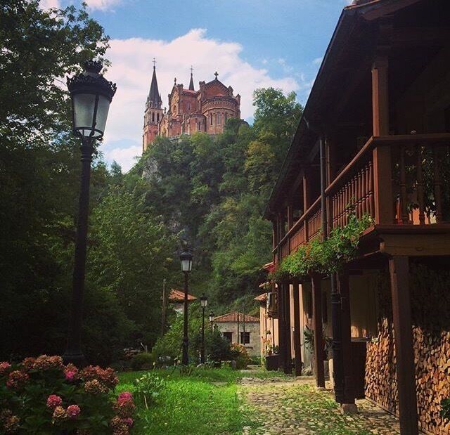 A cobblestone path, wooden buildings, and a castle on a hill.