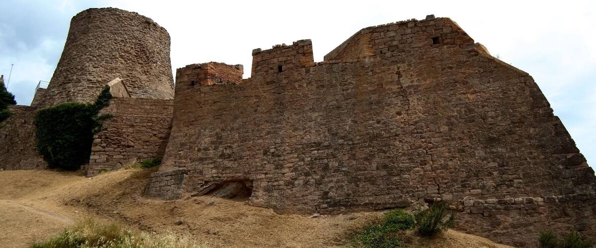 A stone castle with a round tower and a large wall.
