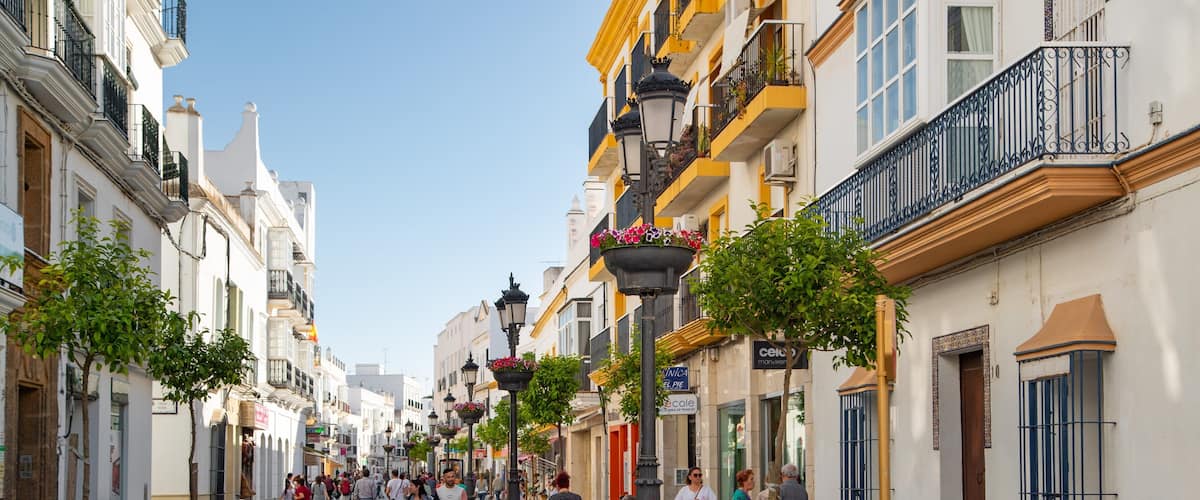 A bustling street lined with historic buildings, pedestrians, and decorative street lamps.