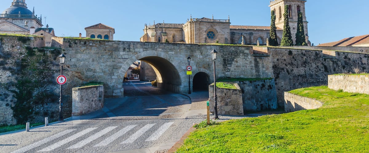 A stone bridge with arches, a cathedral with a dome, and a tower with a clock.