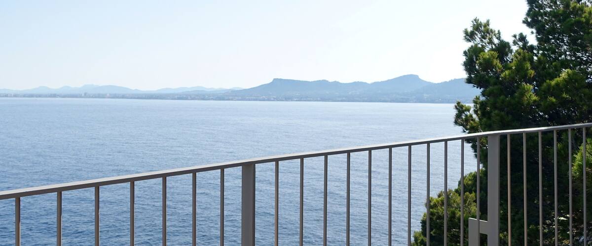 A coastal view with a railing, ocean, and distant mountains.