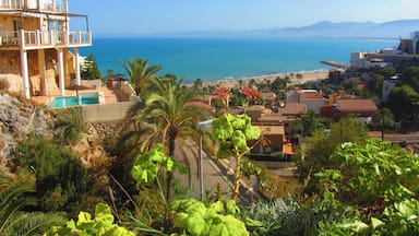 Uma vila costeira com vista clara para o mar, uma piscina e vegetação exuberante.