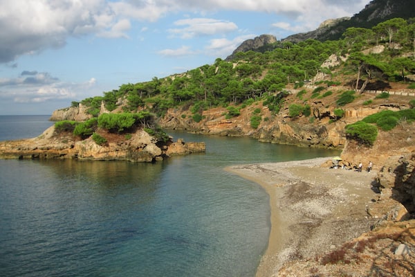 Eine Küstenlandschaft mit schroffen Klippen, klarem, blauem Wasser und grüner Vegetation.