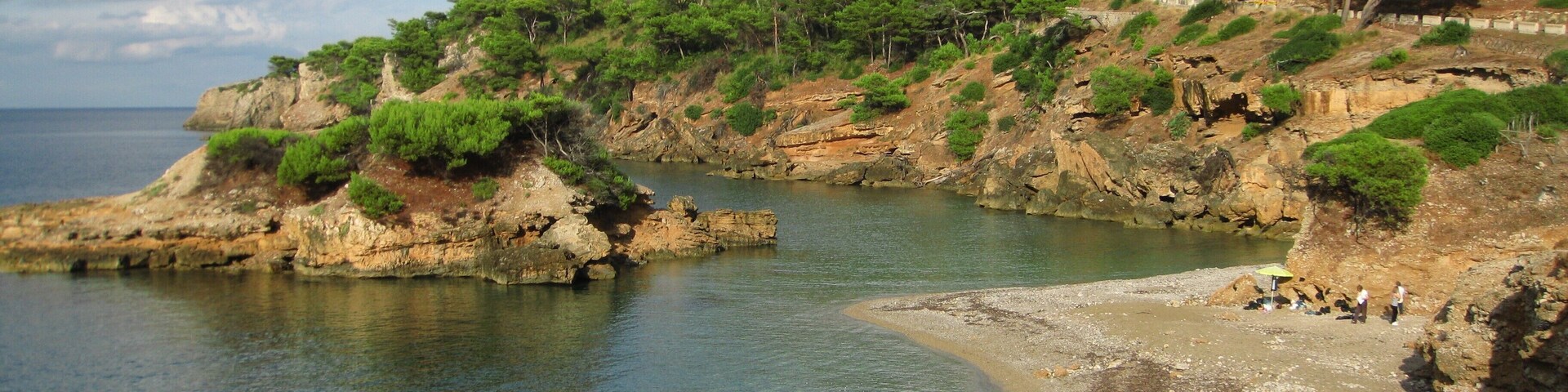 A coastal landscape with rocky cliffs, clear blue water, and green vegetation.