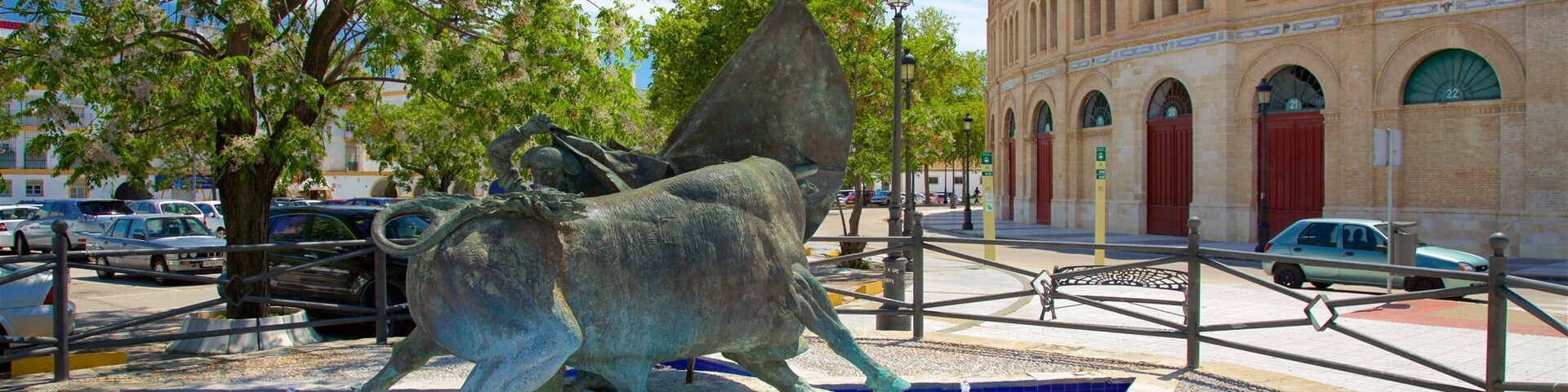 Une statue de taureau en bronze, placée dans une fontaine, avec un bâtiment en arrière-plan.