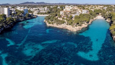 Un pueblo costero con aguas turquesas cristalinas, una isla rocosa y edificios circundantes.