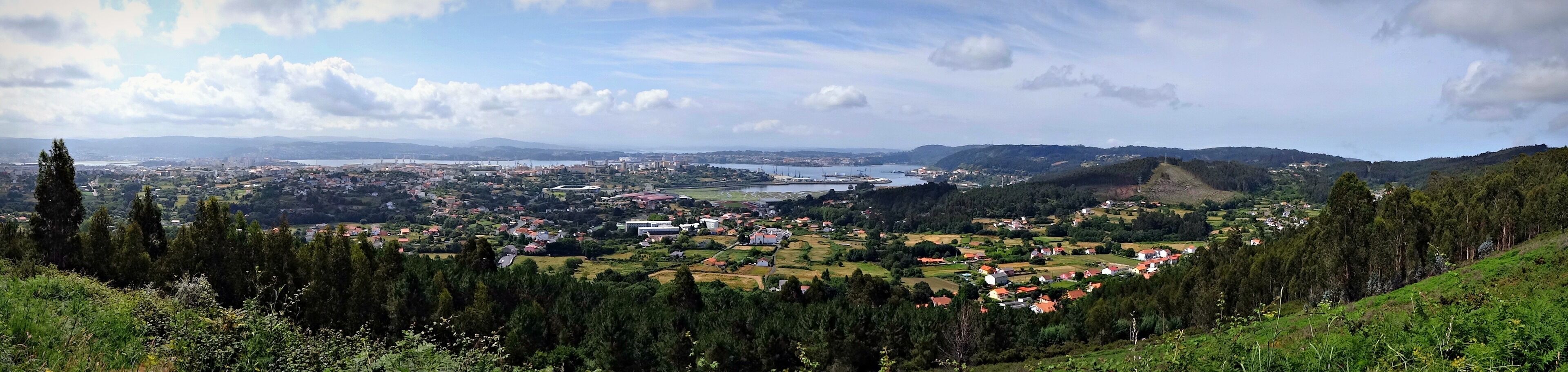 A coastal town with a river, surrounded by hills and greenery.