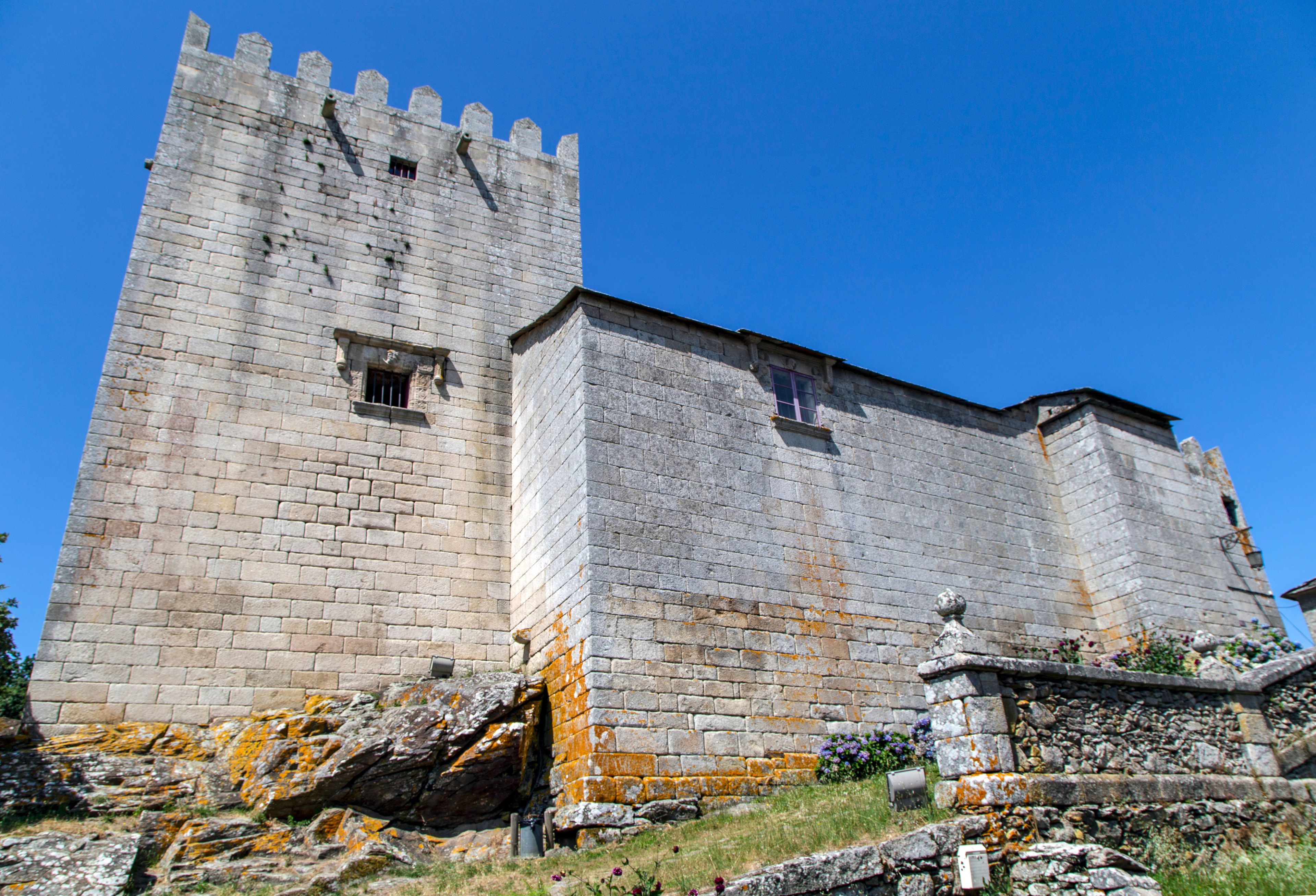 Un castillo de piedra histórico con una torre alta y almenas.