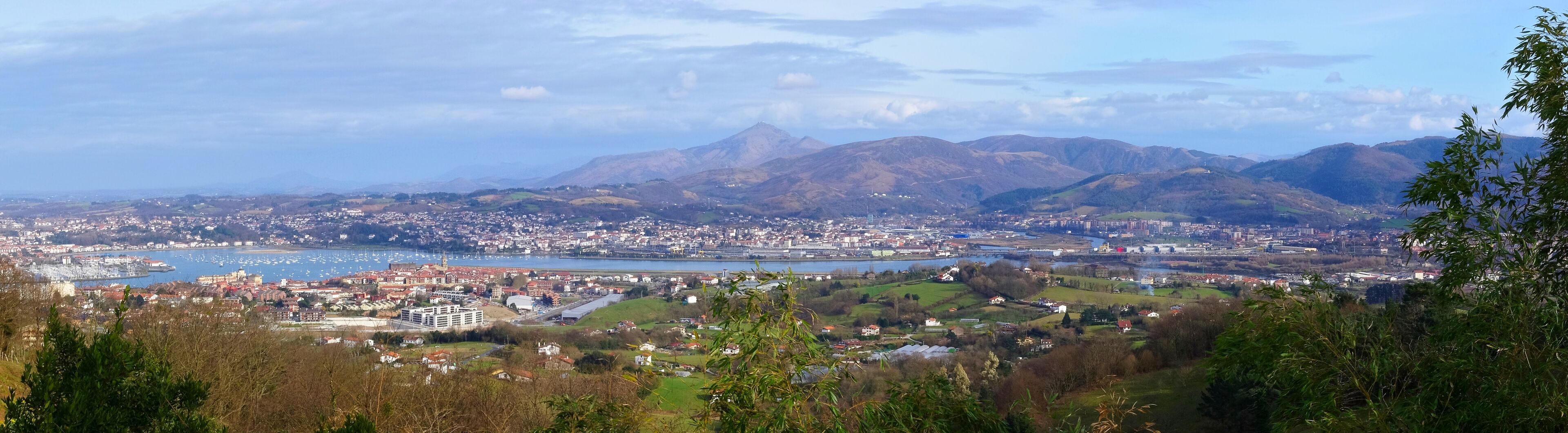 A coastal city with a river, mountains, and a mix of urban and rural landscapes.