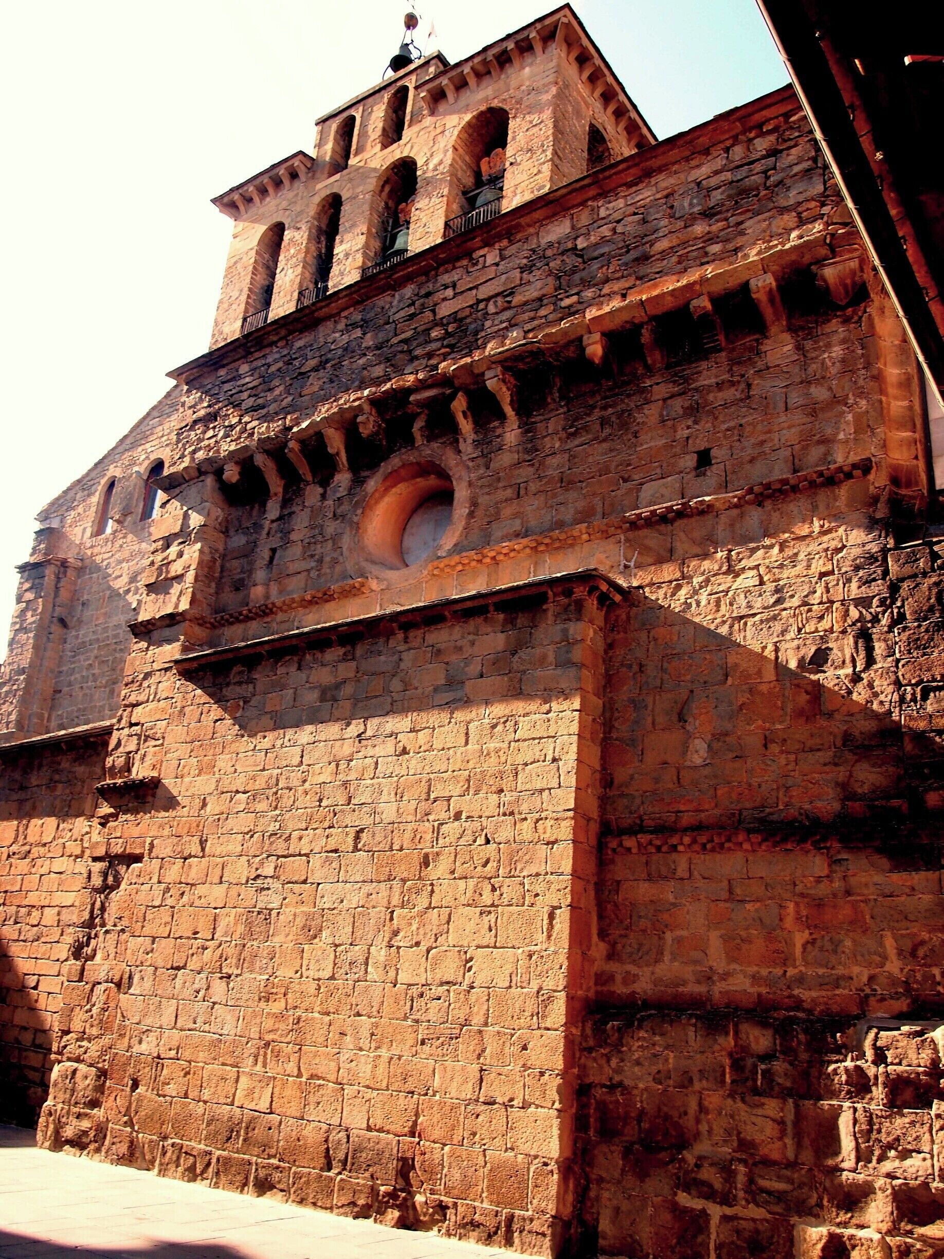 Un edificio histórico de piedra con ventanas arqueadas y un ventanal circular.