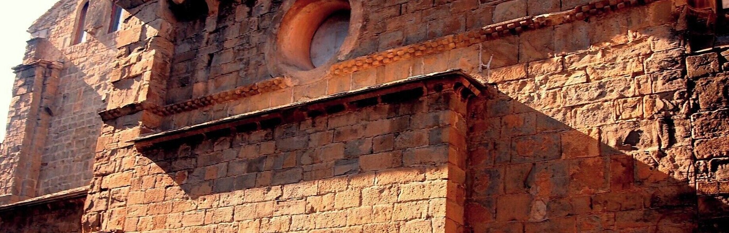 Un edificio histórico de piedra con ventanas arqueadas y un ventanal circular.